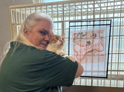 Renee Skipper holding a cat in front of a kennel